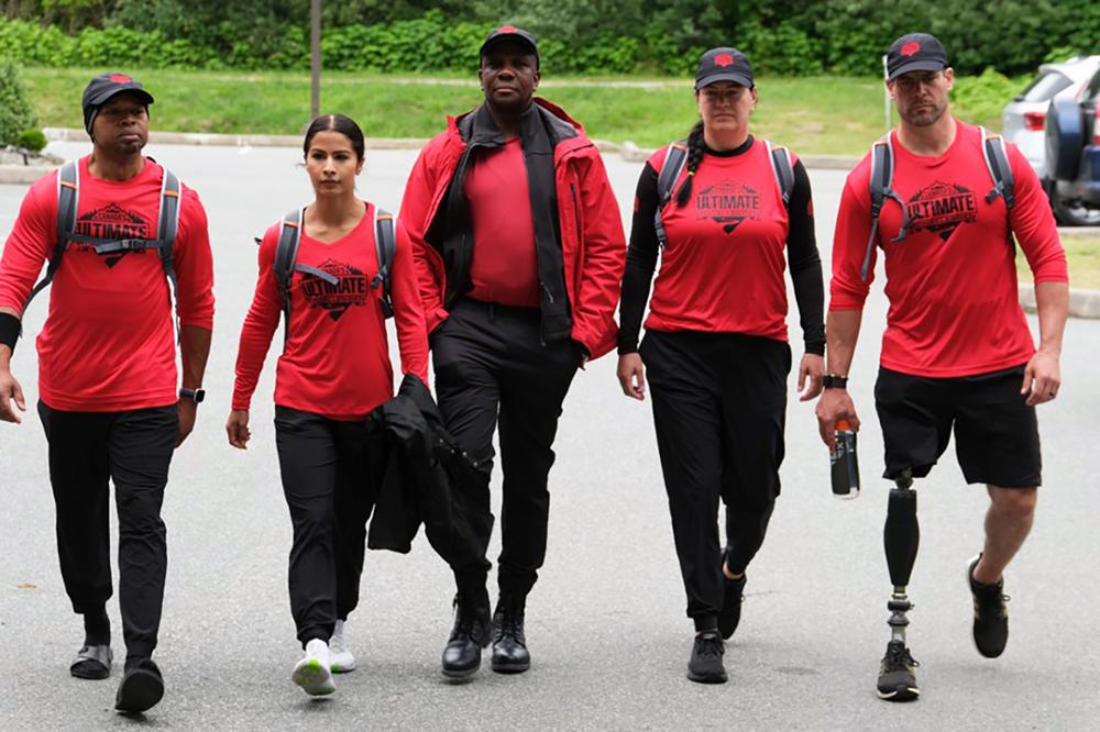 Five people wearing team uniforms are walking down a street.