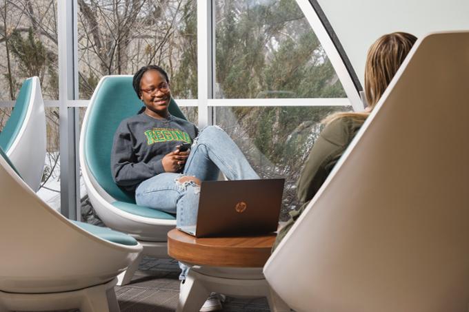 Two students sitting in lounge chairs studying together on campus. having 