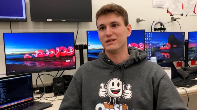 A student doing an interview in front of computers