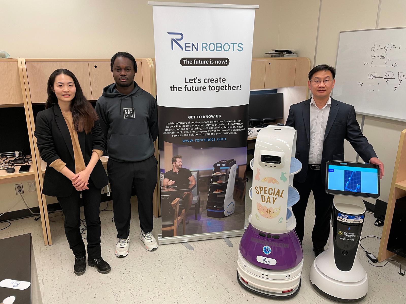 Students and an instructor stand in front of a trade show booth for robots