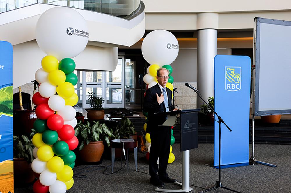 A man speaks at a podium in front of RBC banners and balloon displays