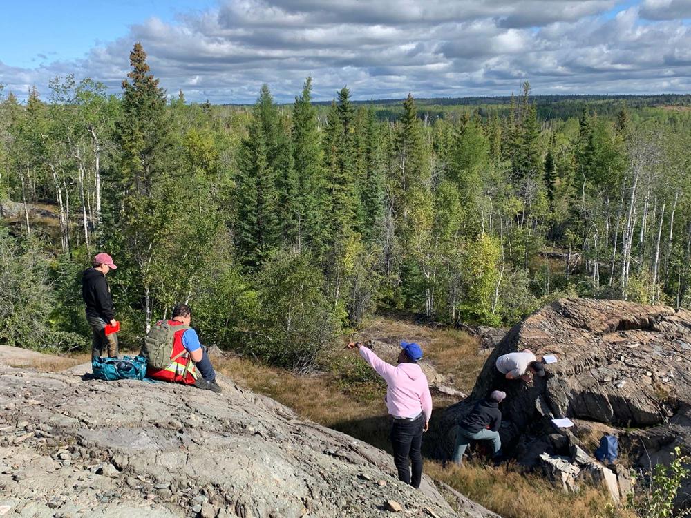 Four students sitting on a rock.