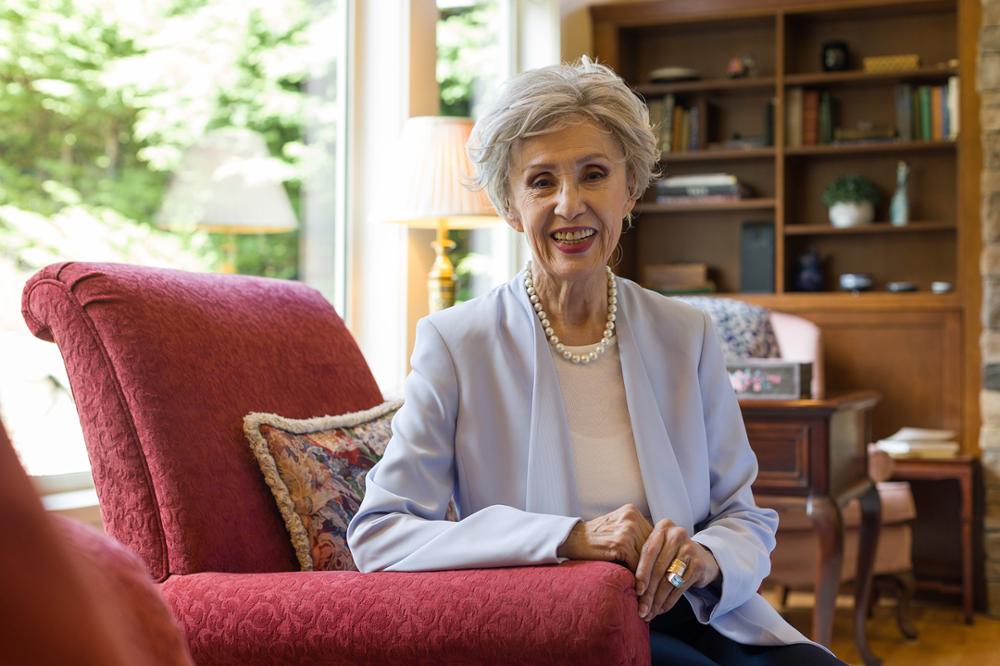 A woman poses in a chair in a sunny living room