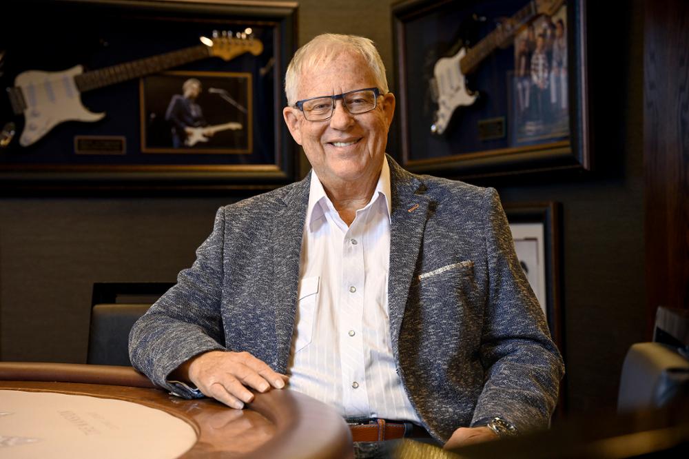 A man smiles and poses for the camera at a large desk