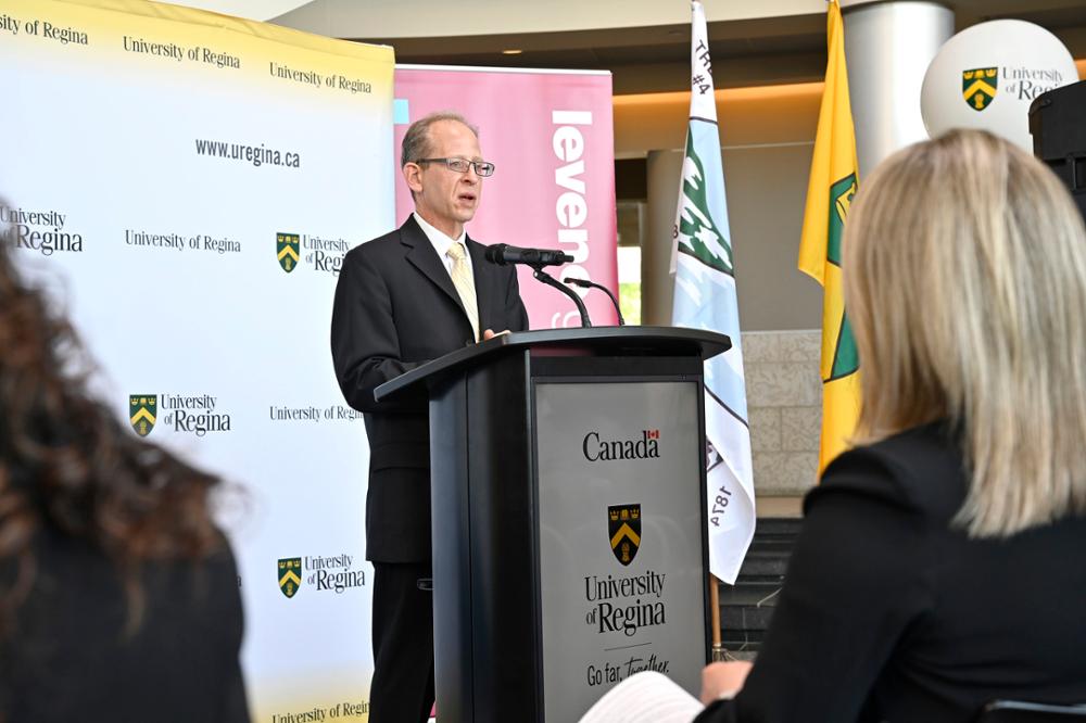 Man standing behind podium and addressing crowd at a media event