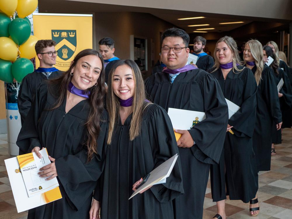 Students standing around in graduation robes.