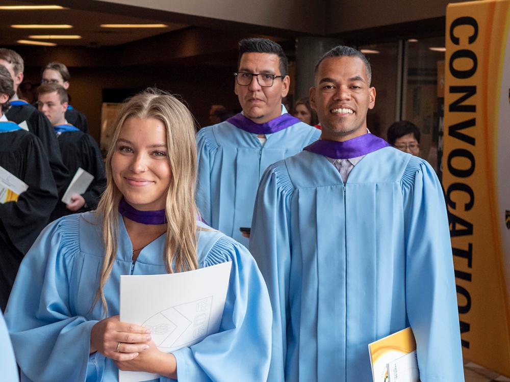 Three students in blue graduation robes