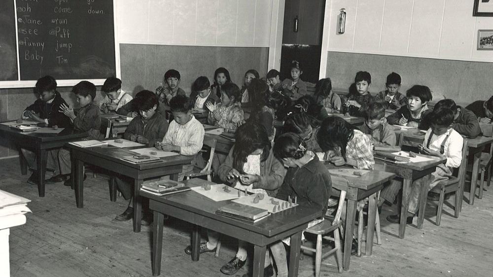 A decades-old photo of Indigenous students in a Residential School classroom.