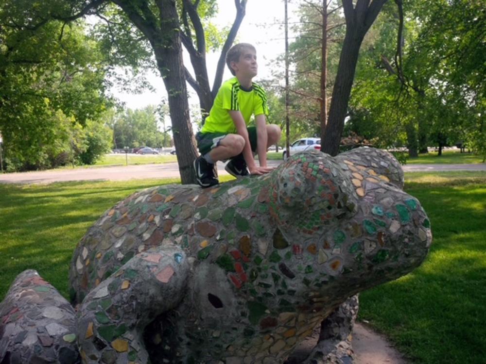 A child sits on a statue of a frog