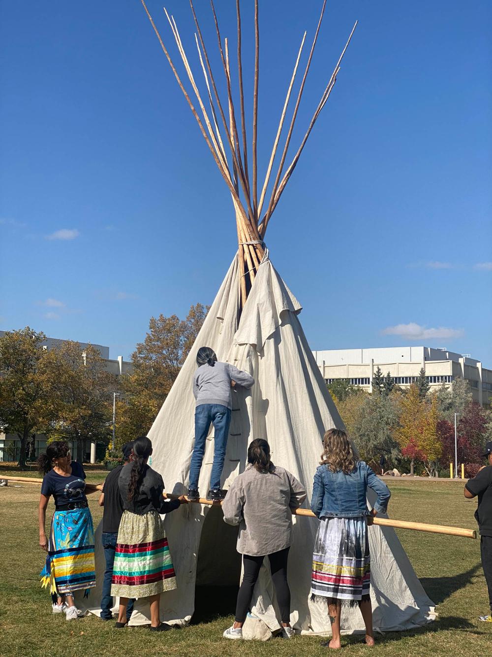 Team members assemble a tipi