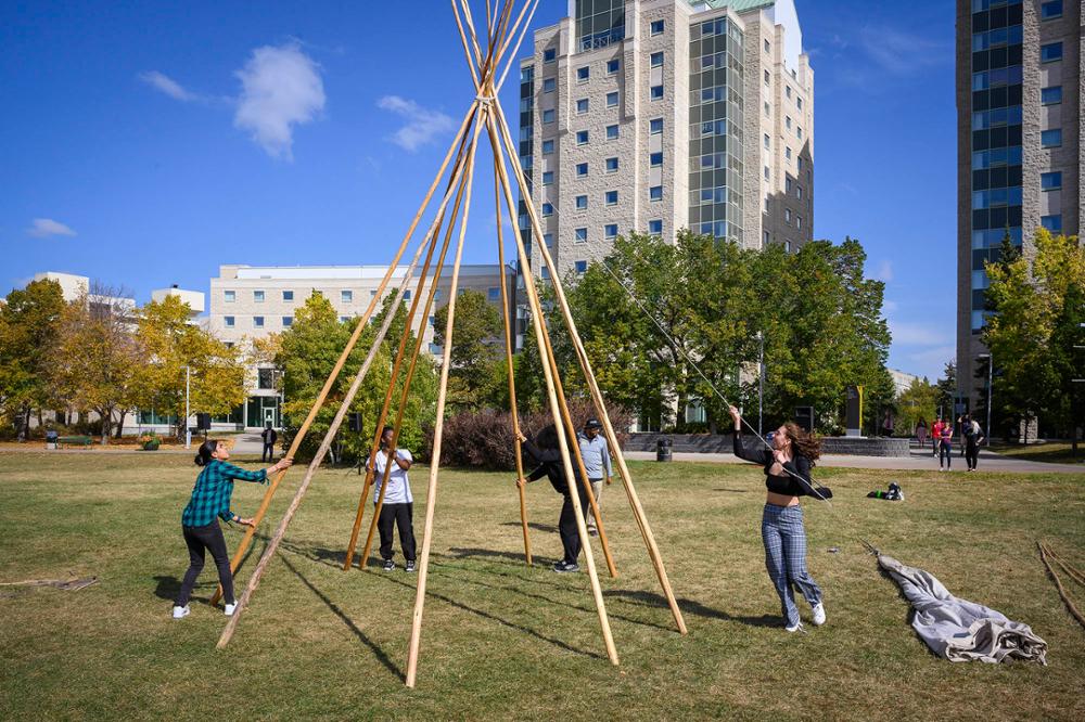 Team members assemBling a tipi