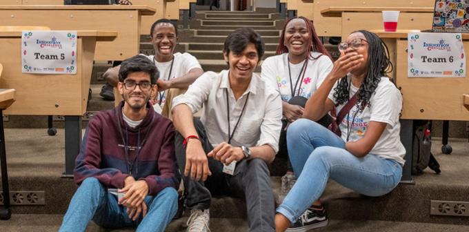 Five students sitting on classroom steps laughing and smiling together