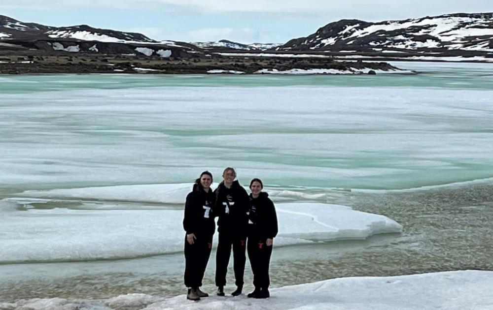 Three people standing outside with ice and snow around them