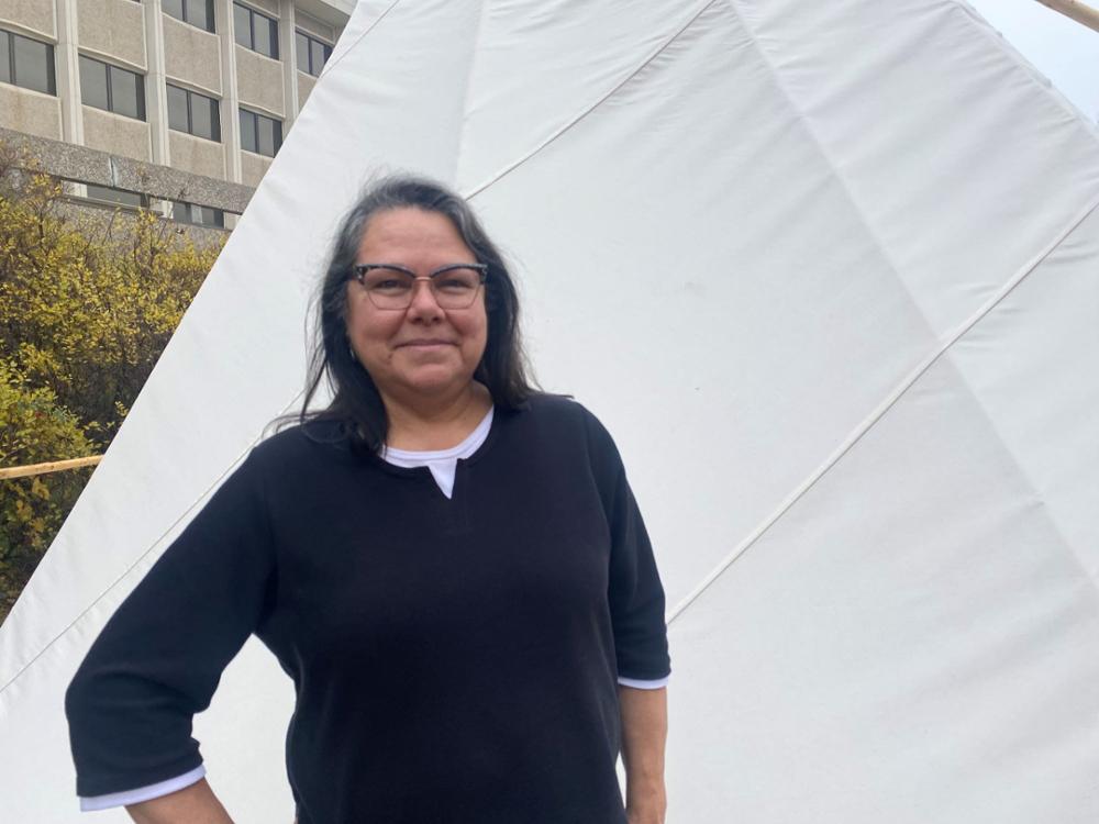 Woman posing for the camera in front of a tipi