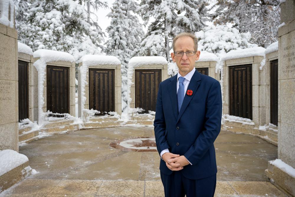 A man in a suit standing at a memorial