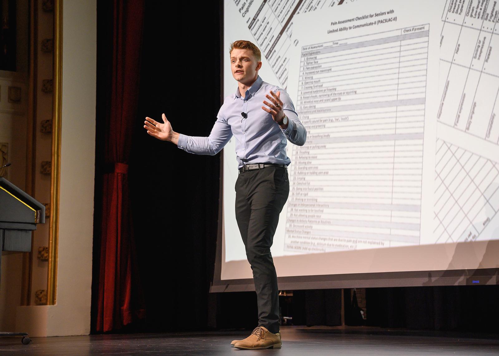 A student presenting in front of a display screen.