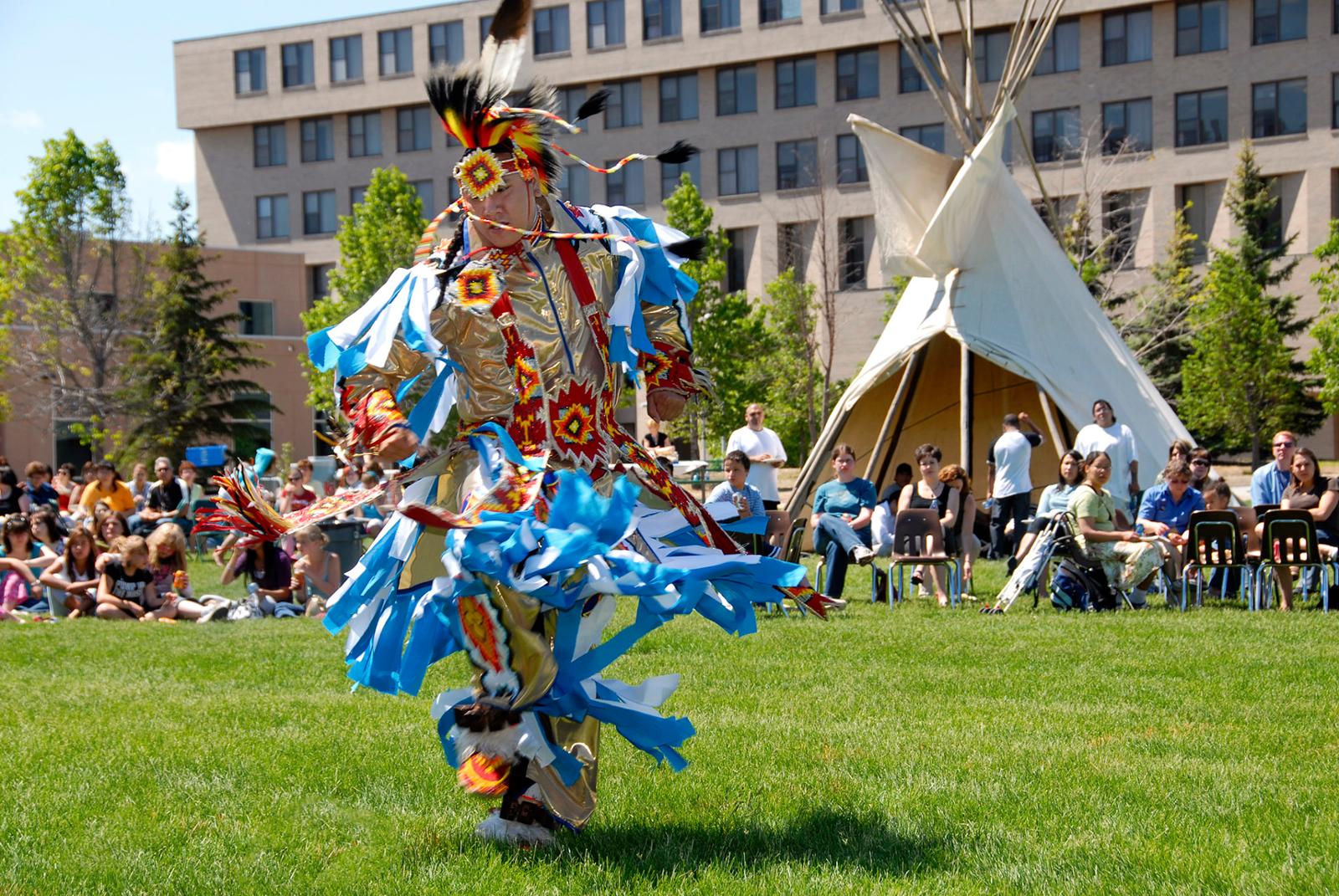 An Indigenous dancer dances with tradition attire.