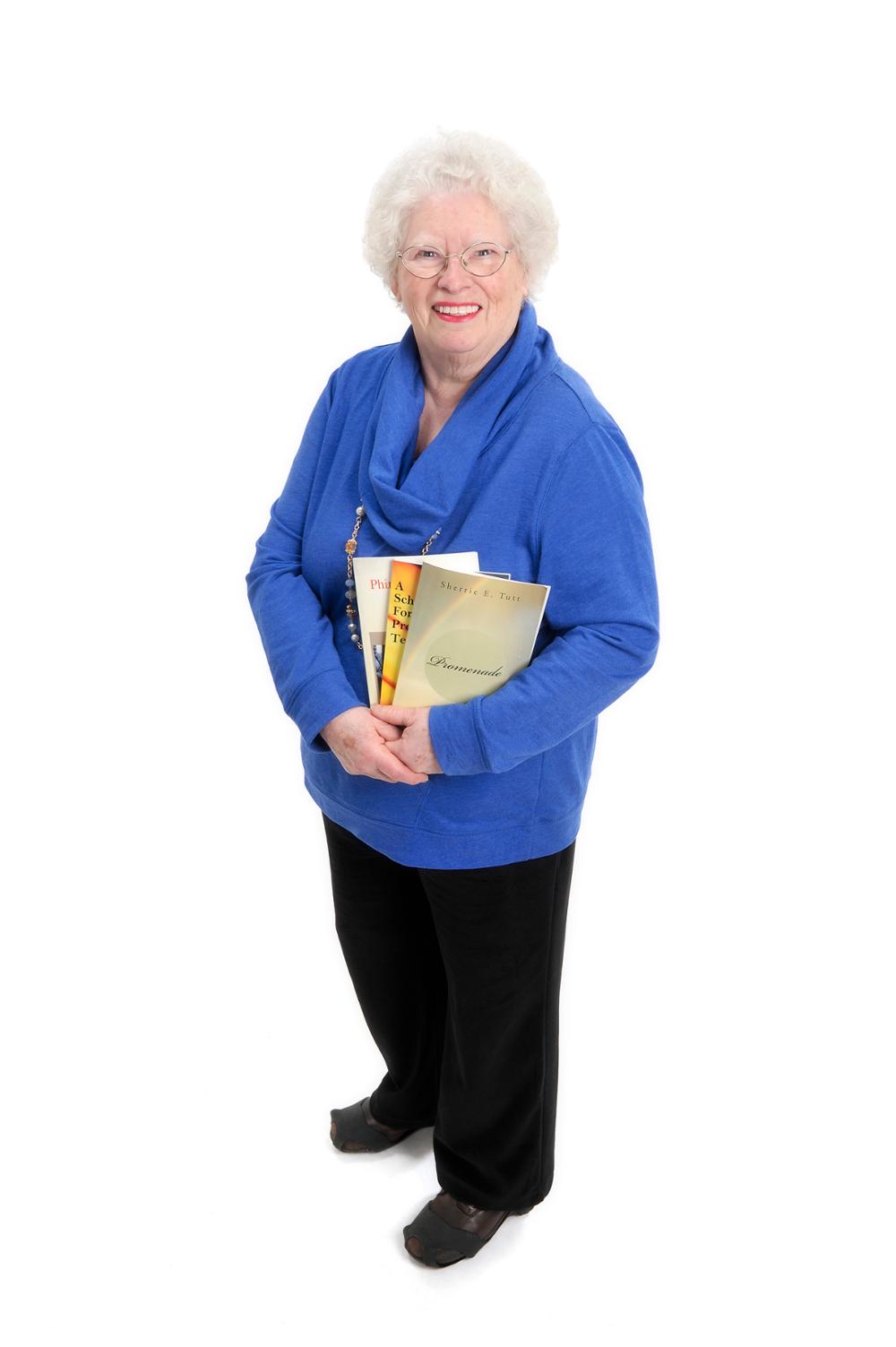 Senior citizen holding three of the five books that she has had published.