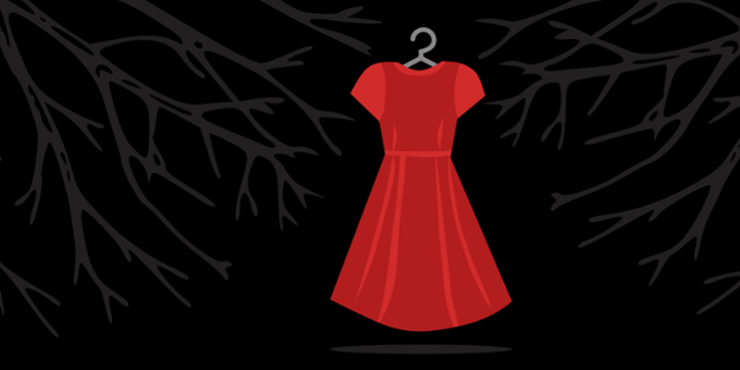 A single red dress hangs on a coat hanger in front of a dark wooded area
