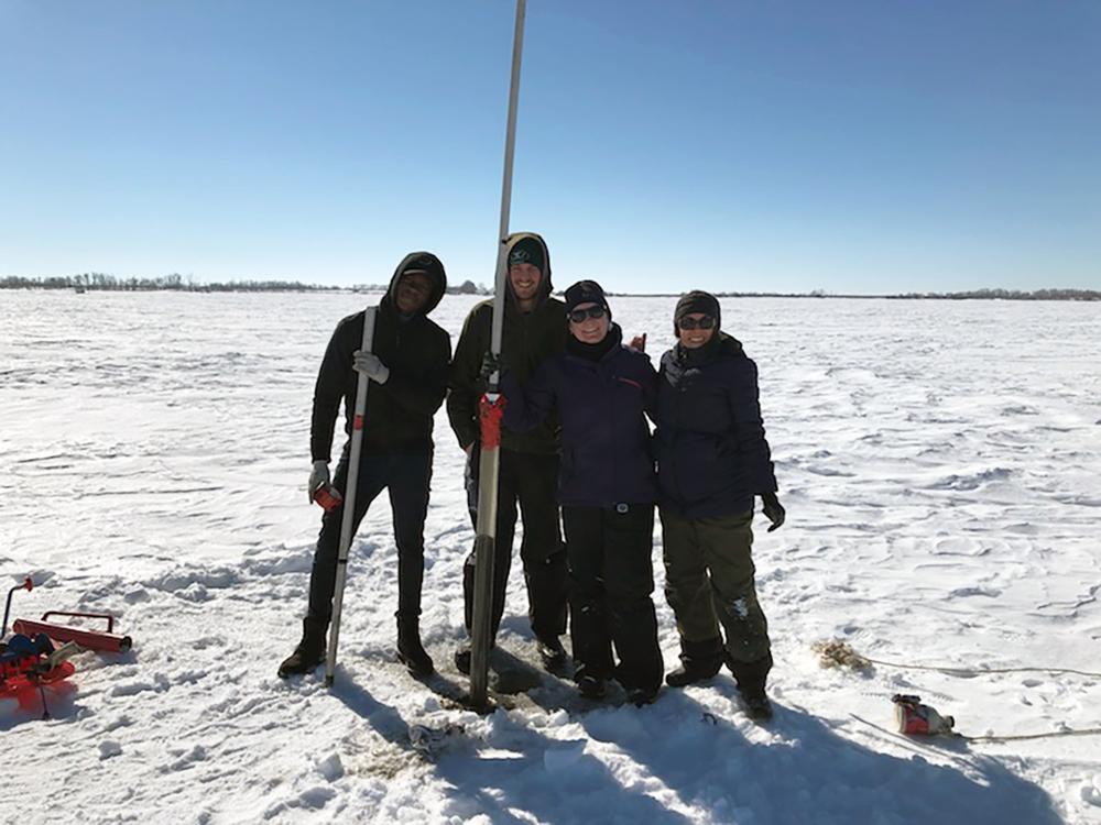 Professor and students standing on frozen lake in Saskatchewan taking core samples.