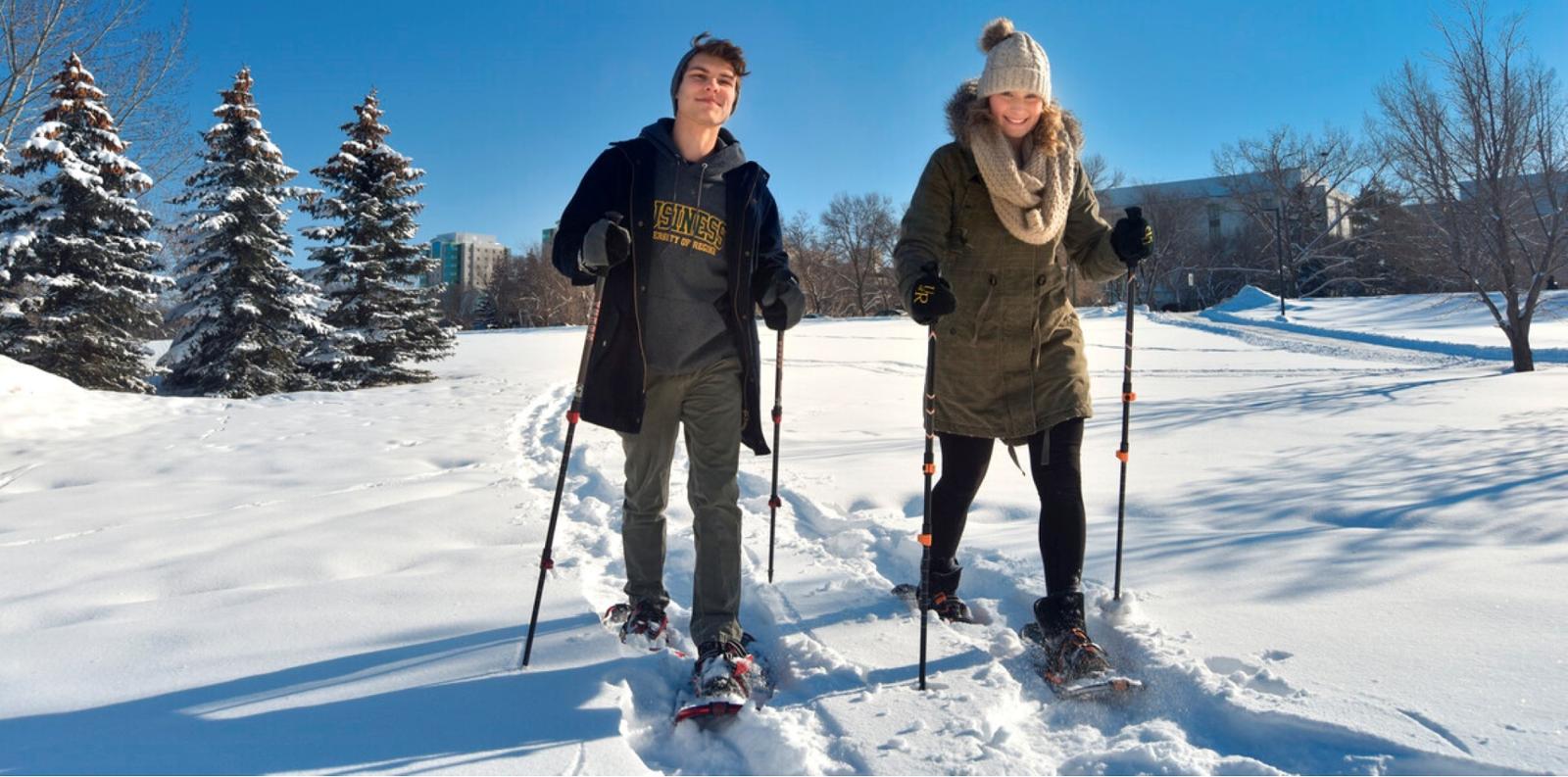 Two students Nordic skiing on campus.