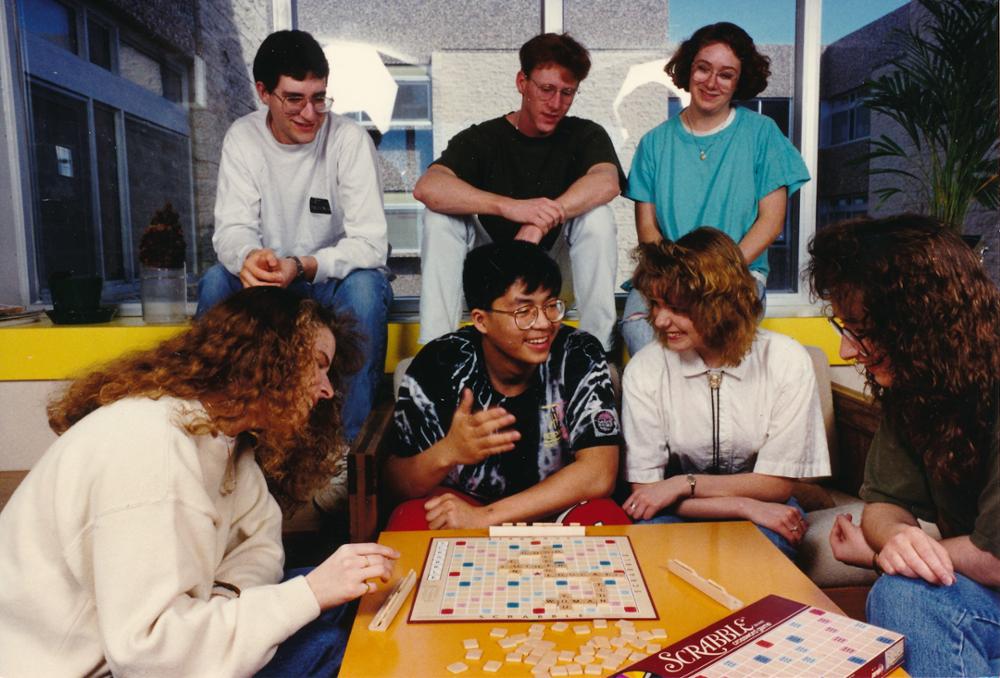 A group of individuals socializing and playing Scrabble.