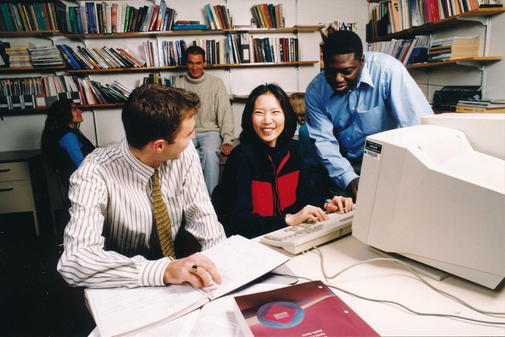 Three individuals sitting in front of a computer.