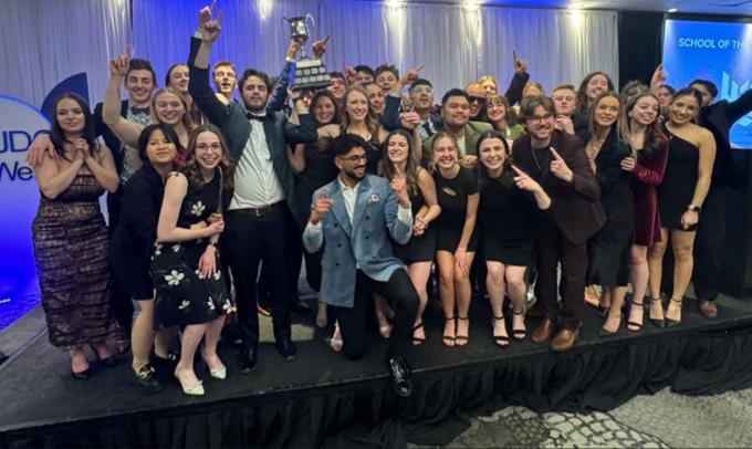 A large group of individuals with a trophy.