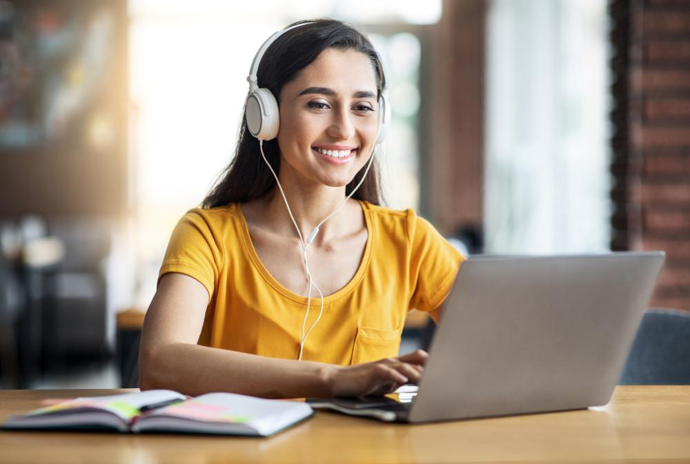 Alt text: Individual sitting in front of laptop with headphones on.