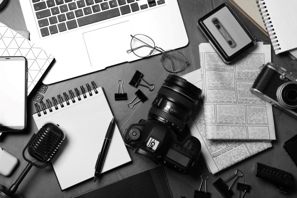 photo of items on a desk: camera, notepad, microphone, etc.