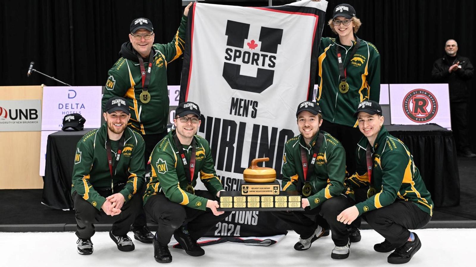 Six men in U of R curling team uniforms hold U SPORTS banner and trophy