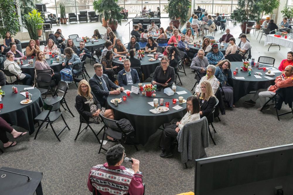 People seated at dining tables listening to speaker.