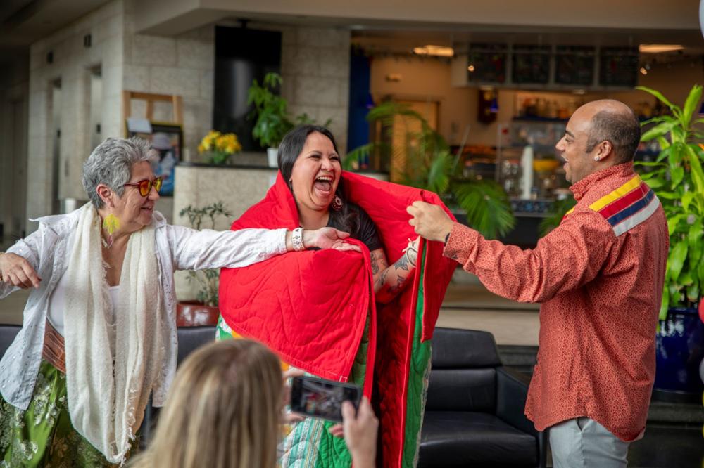 Smiling student is presented with a star blanket.