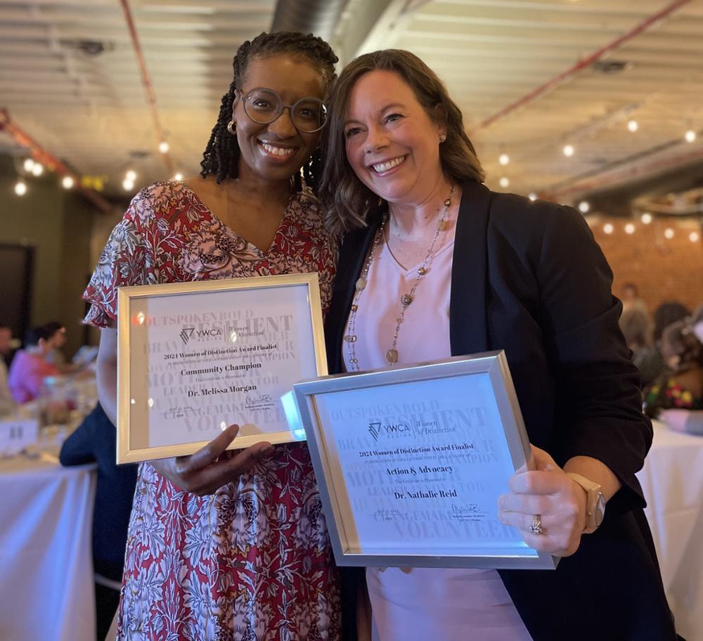 Two individuals standing side by side holding framed certificates.