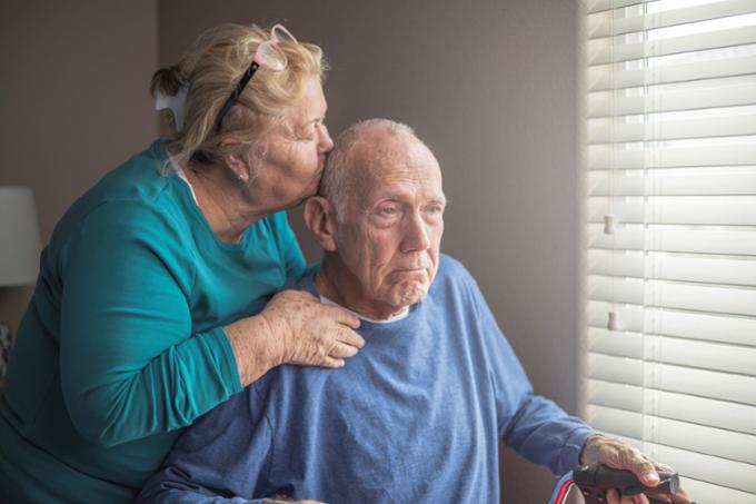 A woman kissing a man that is sitting