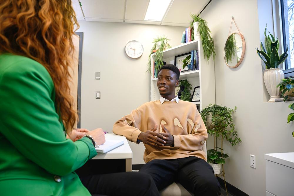 Two individuals talking at a desk.