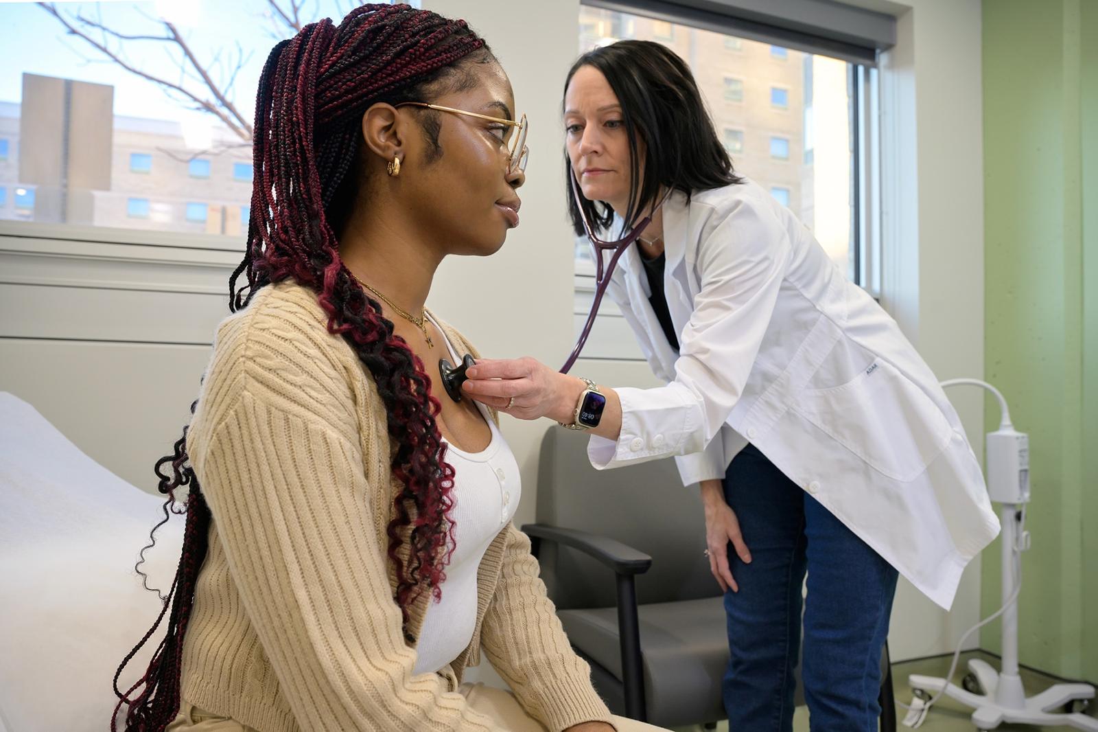 A nurse checking a patient’s heart with a stethoscope.