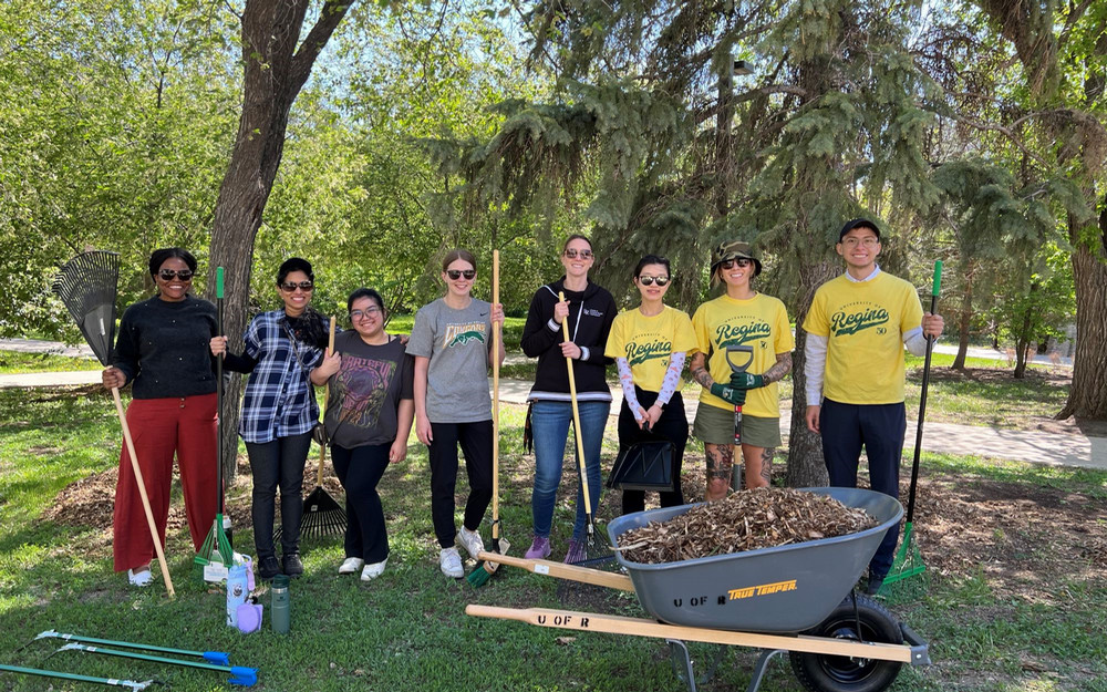 8 people holding rakes and shovels