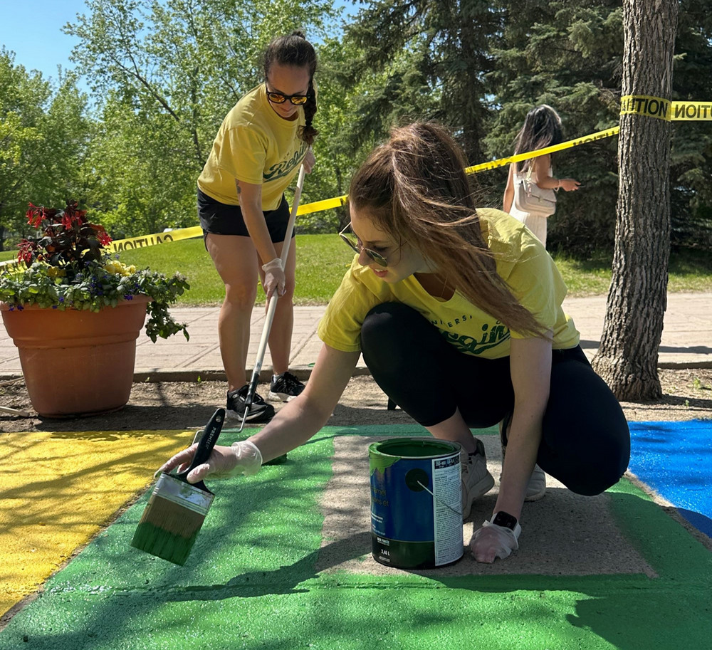 two people painting a sidewalk