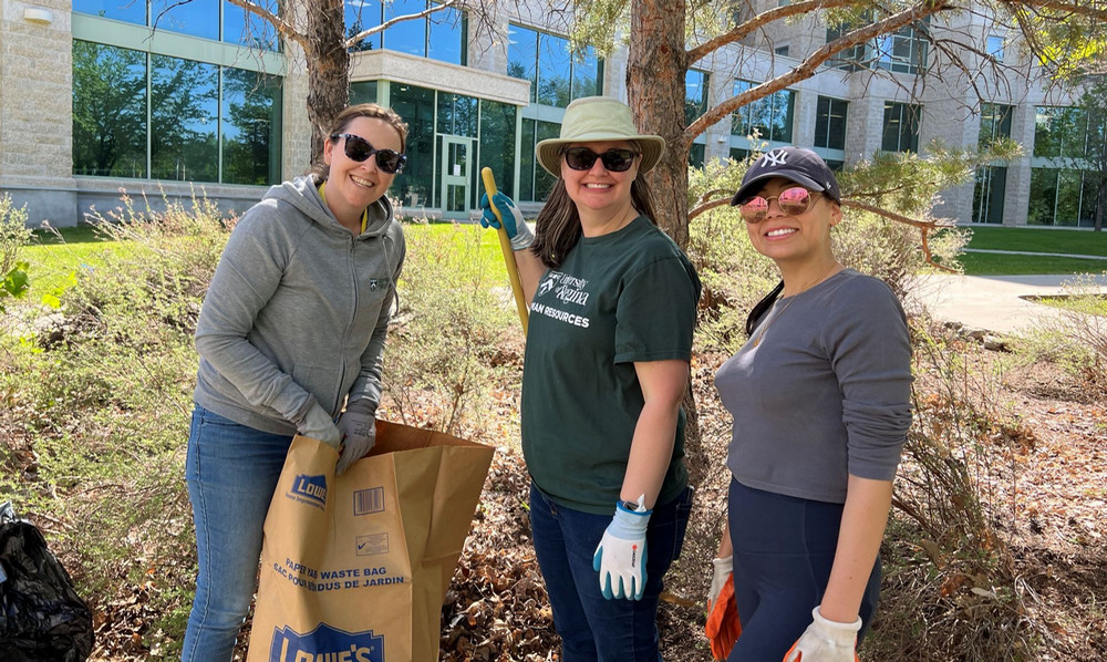 three people raking leaves