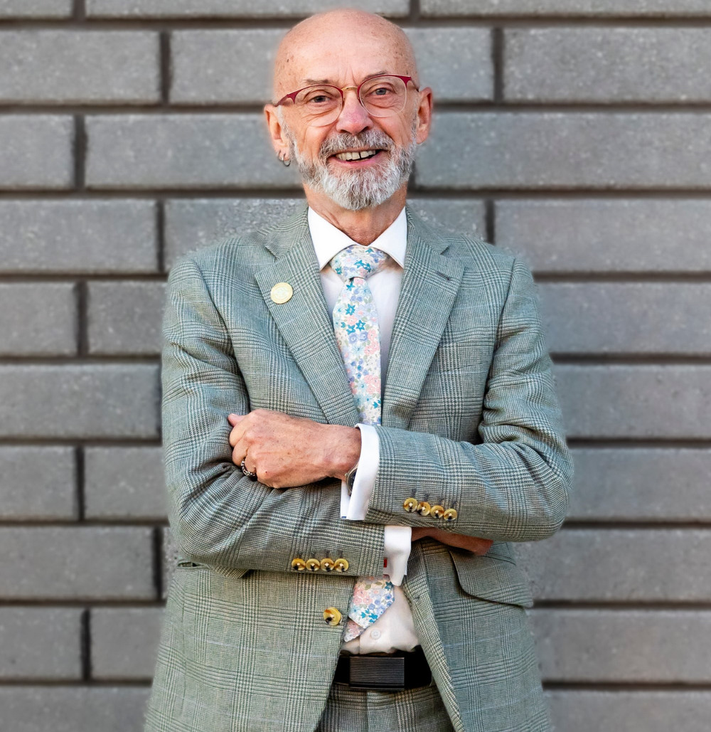 a smiling man standing in front of a wall