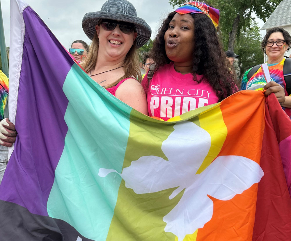 Two people holding a colourful flag