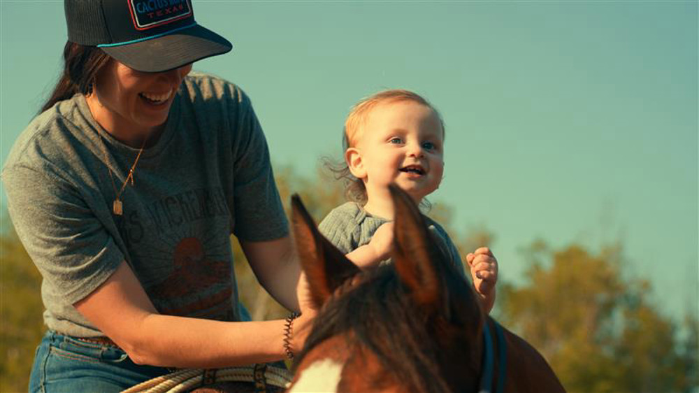Young woman on a horse with her young daughter.
