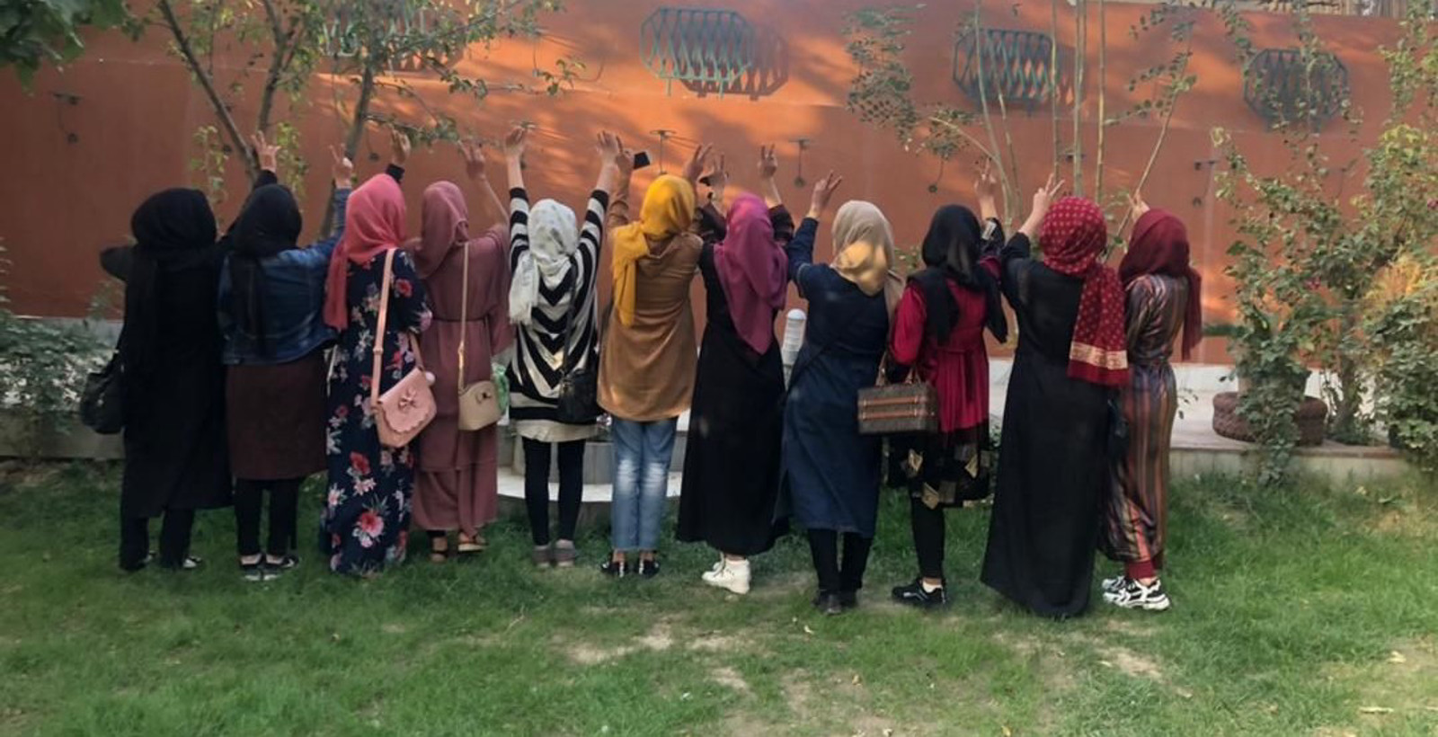 a group of women standing facing a wall