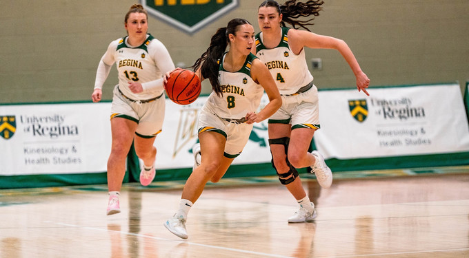 Three women on a basketball court playing.