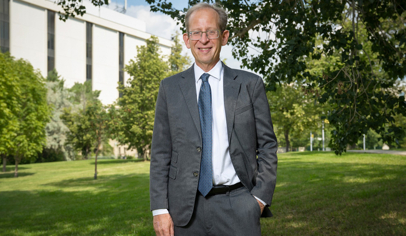 a smiling man standing outdoors on campus