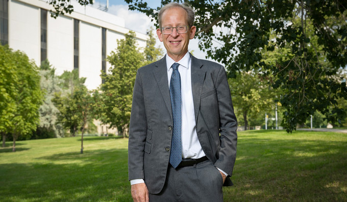 a smiling man standing outdoors on campus