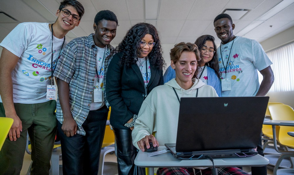 a group of smiling people looking at a laptop