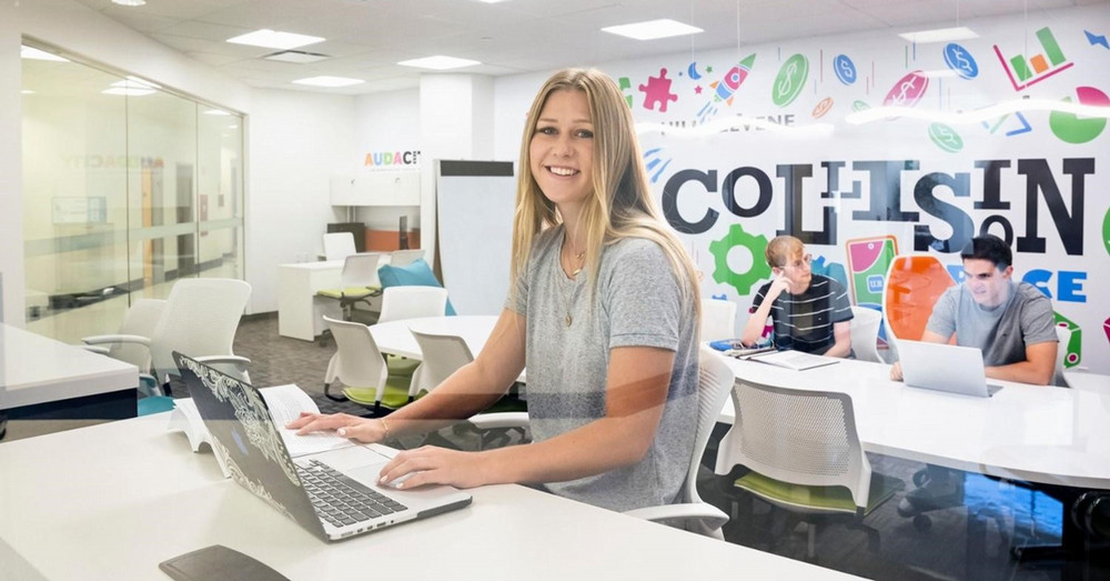 a smiling person using a laptop on a table