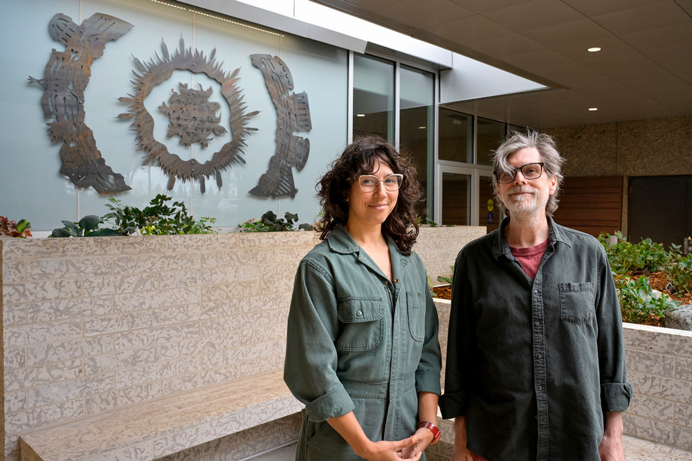 two people standing in front of a piece of artwork